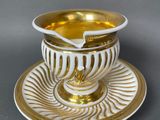 a white and gold cup and saucer on a saucer