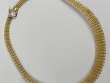 gros plan d'un collier en or sur une surface blanche