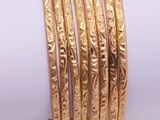 a close up of a stack of gold bracelets on a white surface