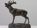 statue of a stag standing on a rock in front of a gray wall