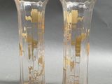 two vases with gold designs on them on a gray surface