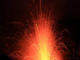 une image d'un volcan crachant de la lave dans les airs, la nuit