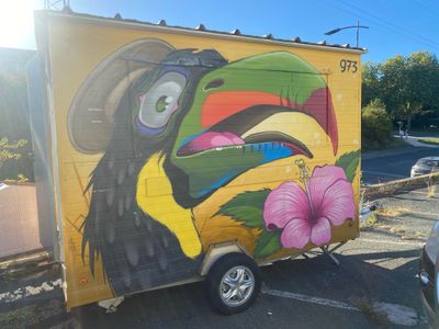 painting on the side of a yellow truck with a toucao on it