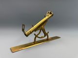 une maquette en laiton ancien représentant un télescope posé sur un socle