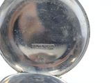 a silver pocket watch sitting on top of a white table