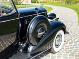 an old black car parked on a cobblestone road