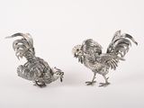 paire de figurines de coqs plaquées argent sur fond blanc