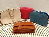 four purses are lined up on a striped table cloth