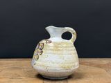 un petit vase blanc posé sur une table en bois