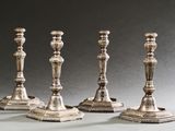 quatre bougeoirs en argent sont alignés sur une table