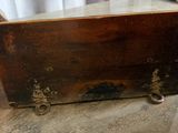 an old wooden box sitting on the floor next to a window