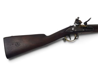 un vieux fusil avec un canon en bois et des garnitures en laiton