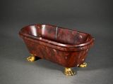 an antique cast iron claw foot bathtub with a red marble finish