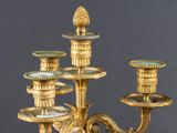 an antique brass candelier with five candles and a pineapple on the top