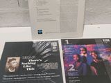 two cd ' s sitting on top of a white table next to a wall