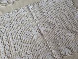 a white crocheted table cloth on a bed