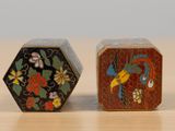 two small boxes with different designs on them on a table