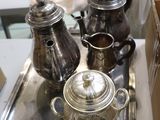three silver teapots sitting on a tray on a table