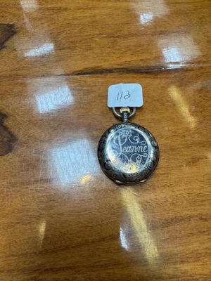 a small silver pocket watch on a wooden table