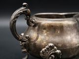 an old silver pot with a handle on a black background
