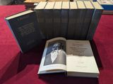 Plusieurs livres sont empilés sur une table recouverte d'une nappe rouge.