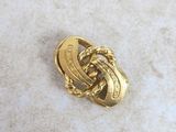 a close up of a gold pin with a knot on it