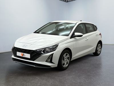 Une voiture blanche est garée dans une pièce blanche au sol noir.