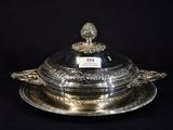 a silver plate with a domed lid on a black background