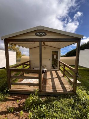 une petite maison avec un porche au milieu de la pelouse