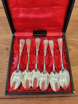 six silver spoons in a red box on a wooden table