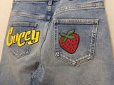 un gros plan sur un jean orné d'un écusson en forme de fraise à l'arrière