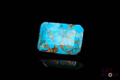 a close up of a turquoise stone on a black surface