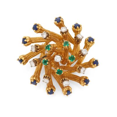 un gros plan sur une broche en or sertie de pierres bleues et vertes
