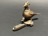 brass figurine of a bird sitting on a wooden spoon