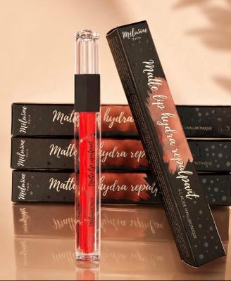 three lip glosses are sitting on top of a stack of books