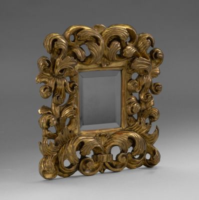an ornate gold frame with a mirror on a grey background