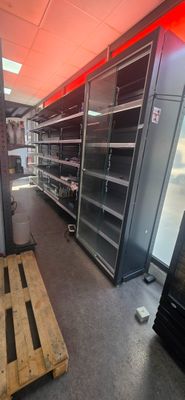 many empty shelves in a store with red lights