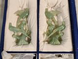 une paire de figurines en jade vert dans une boîte bleue posée sur une table