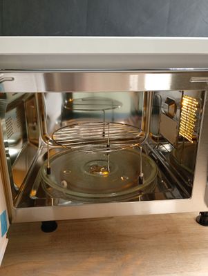 un micro-ondes posé sur le plan de travail, avec une casserole à l'intérieur