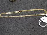 a gold chain with a tag on it next to a pair of scissors