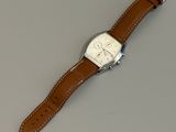 montre-bracelet avec un bracelet en cuir marron sur un fond gris