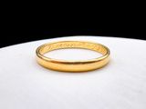 a close up of a gold wedding ring on a white surface