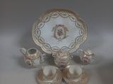 une table blanche avec une assiette dorée, des tasses et des soucoupes