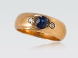 gros plan d'une bague en or avec un saphir et des diamants