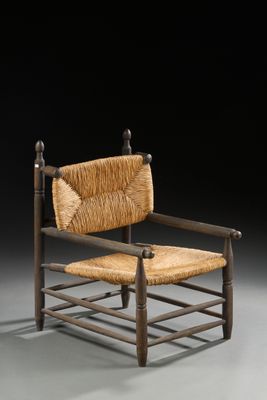 une vieille chaise en bois avec une assise tressée posée sur une surface grise