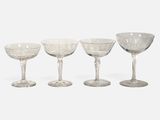 four clear wine glasses sitting on top of each other on a white surface