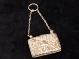 an antique silver purse on a chain on a black background