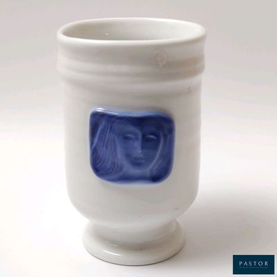 une tasse blanche sur laquelle est dessiné un visage bleu