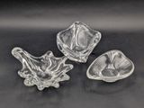 three clear glass dishes on a black surface with a black background