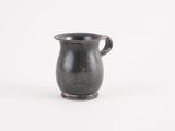 an old black vase with a handle on a white surface